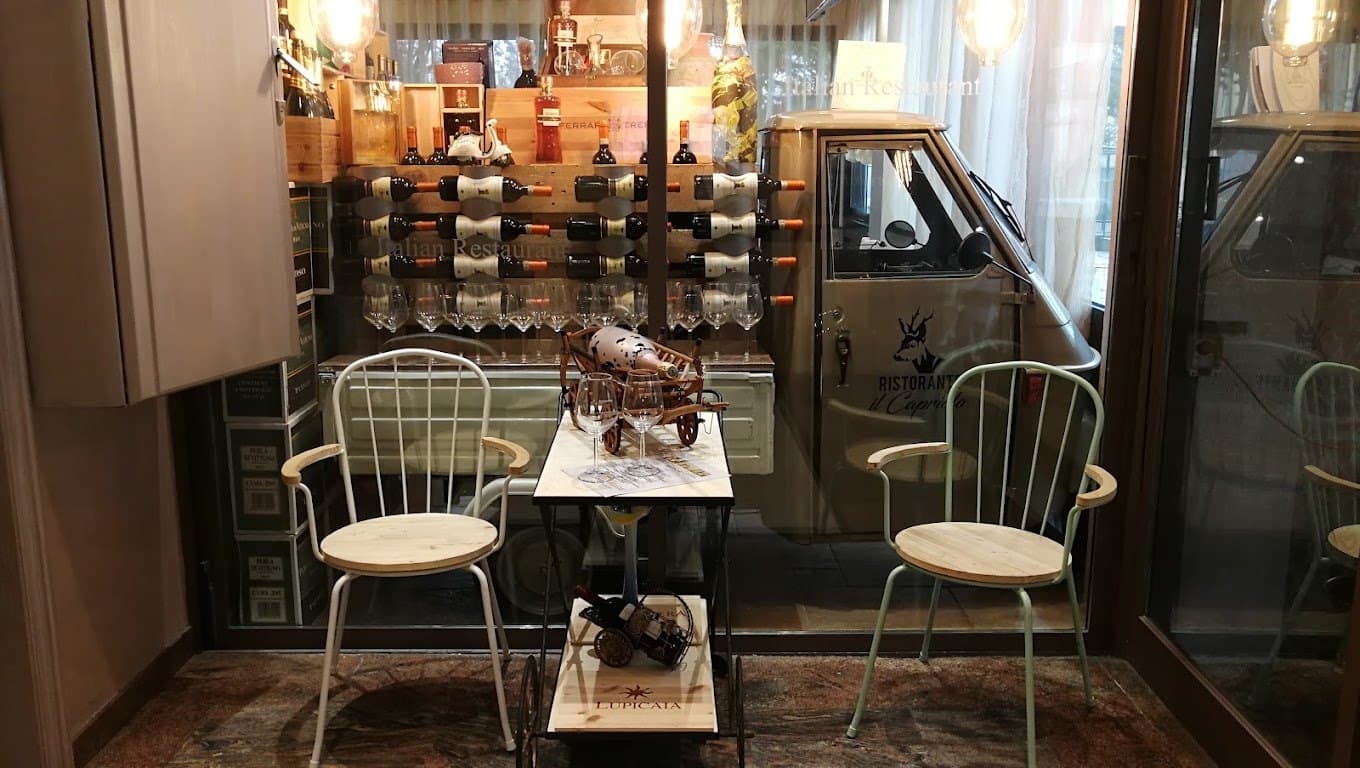 Angolo del ristorante con bottiglie di vino e una piccola Ape decorativa